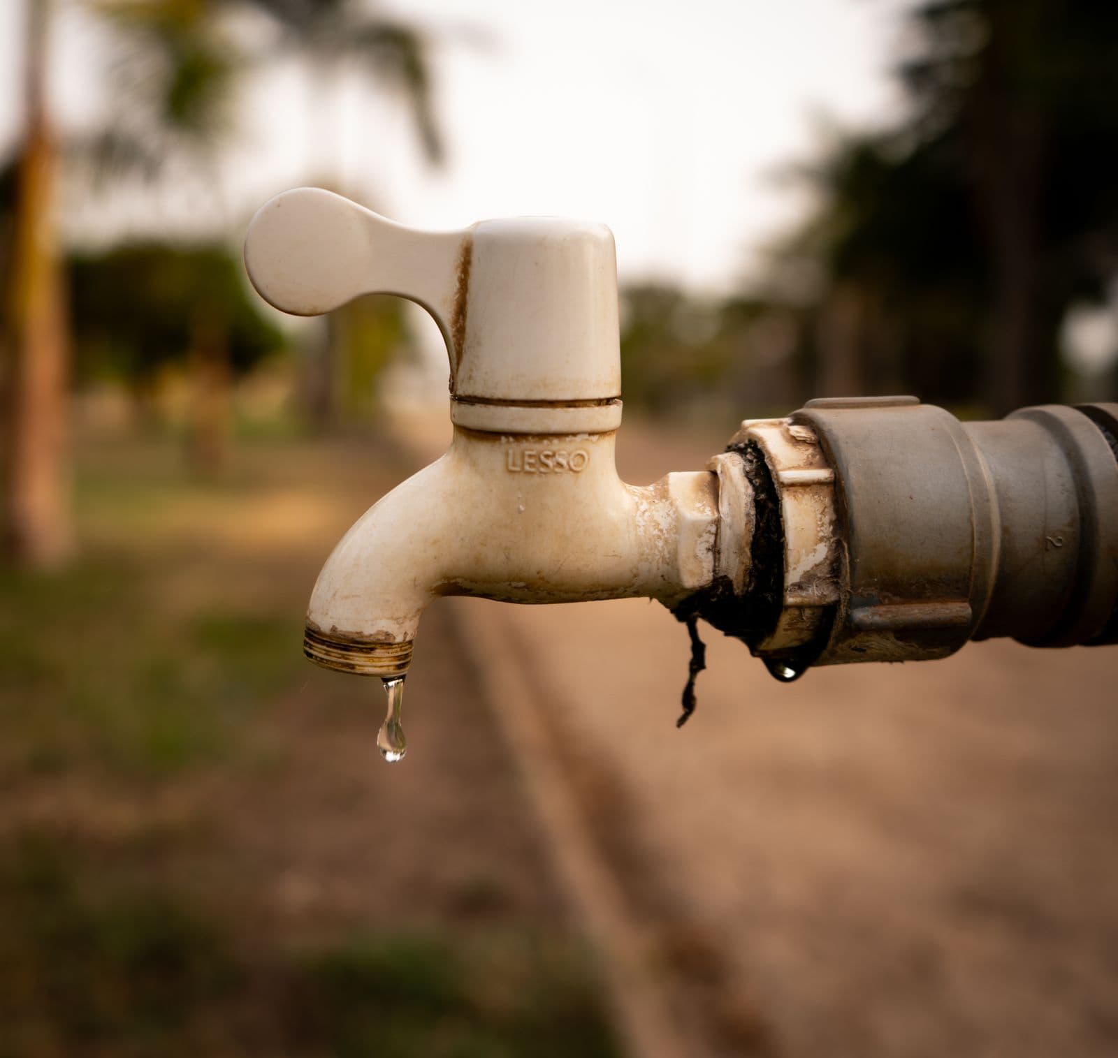 Corroded outdoor water tap dripping from a cracked fitting