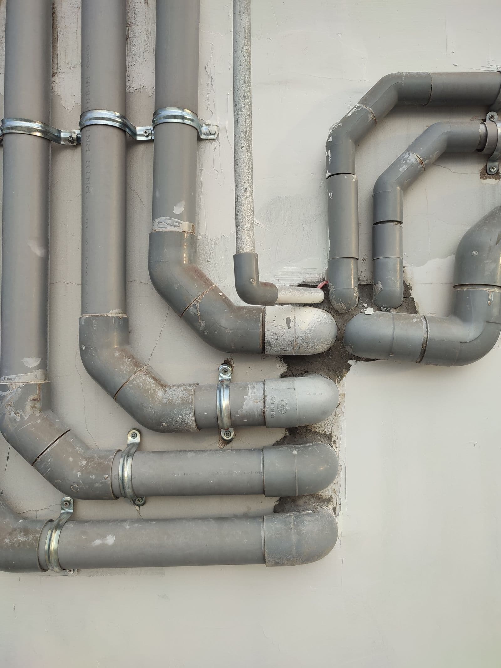 Gray PVC drain pipes running along a wall