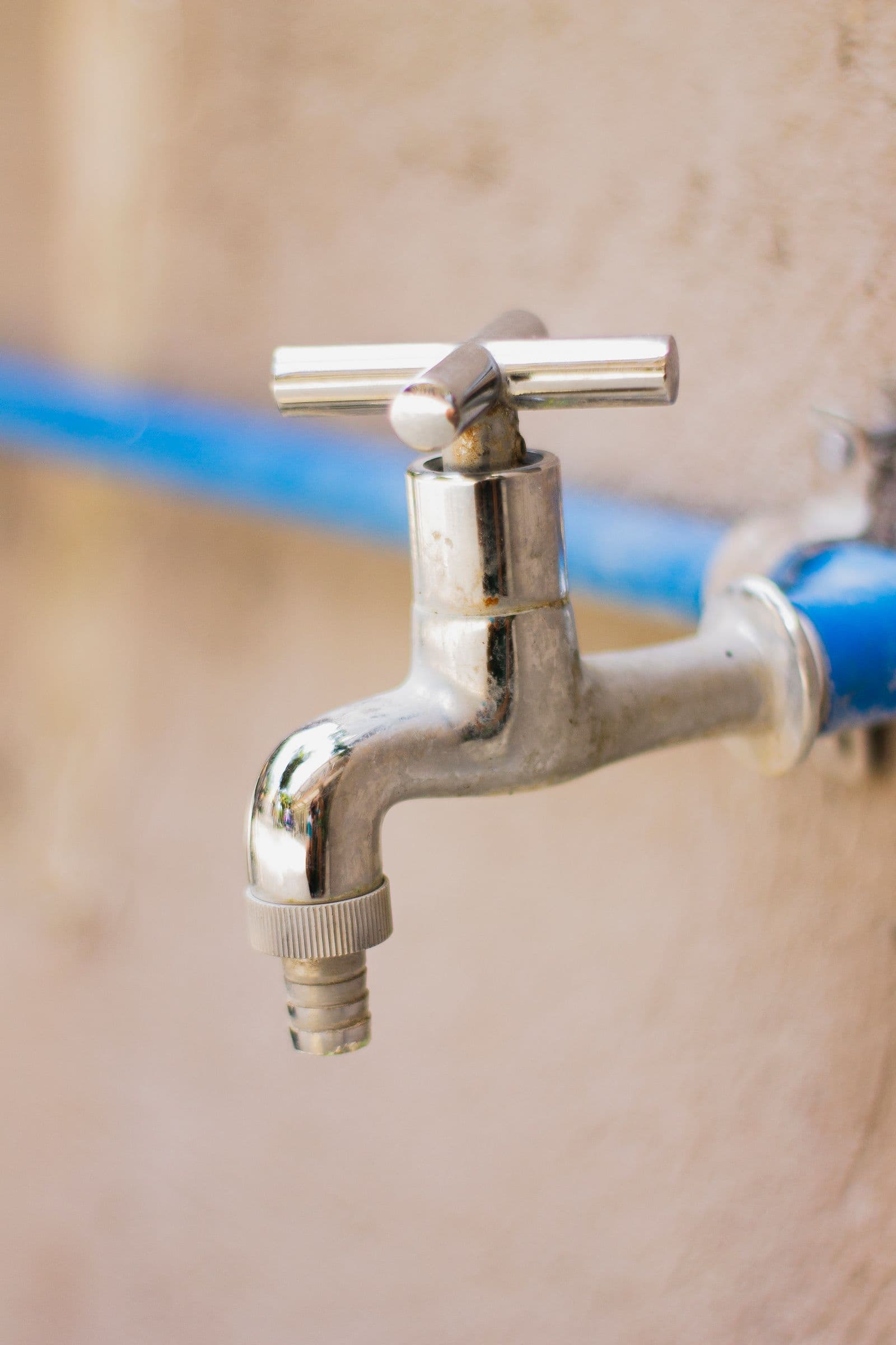 Chrome tap connected to a blue water supply line