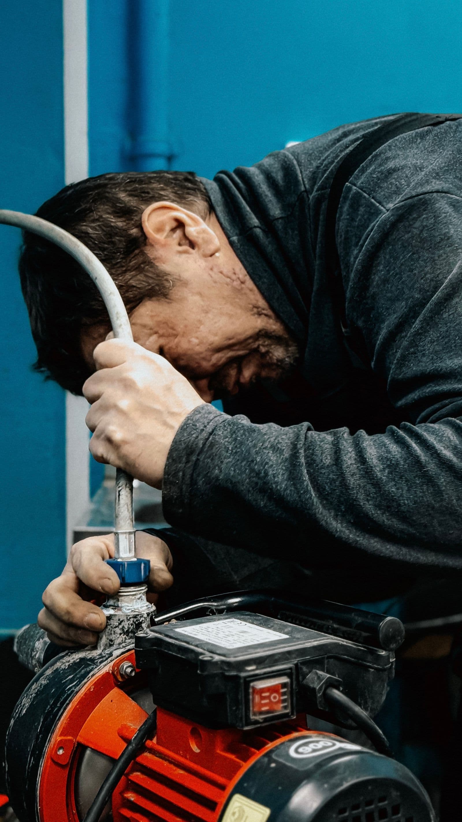 Plumber tightening a supply line connection under a sink